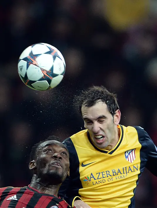 Gelandang AC Milan, Michael Essien berebut bola udara dengan bek Atletico Madrid, Diego Godin selama pertandingan Liga Champion di Stadion Milan San Siro pada 19 Februari 2014. (AFP Photo / Filippo Monteforte)