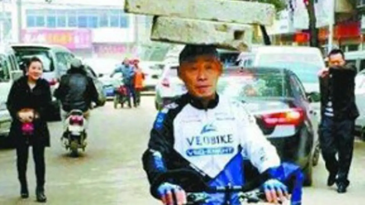 Rahasia Bugar, Pria Ini Naik Sepeda dengan Batu di Atas Kepala