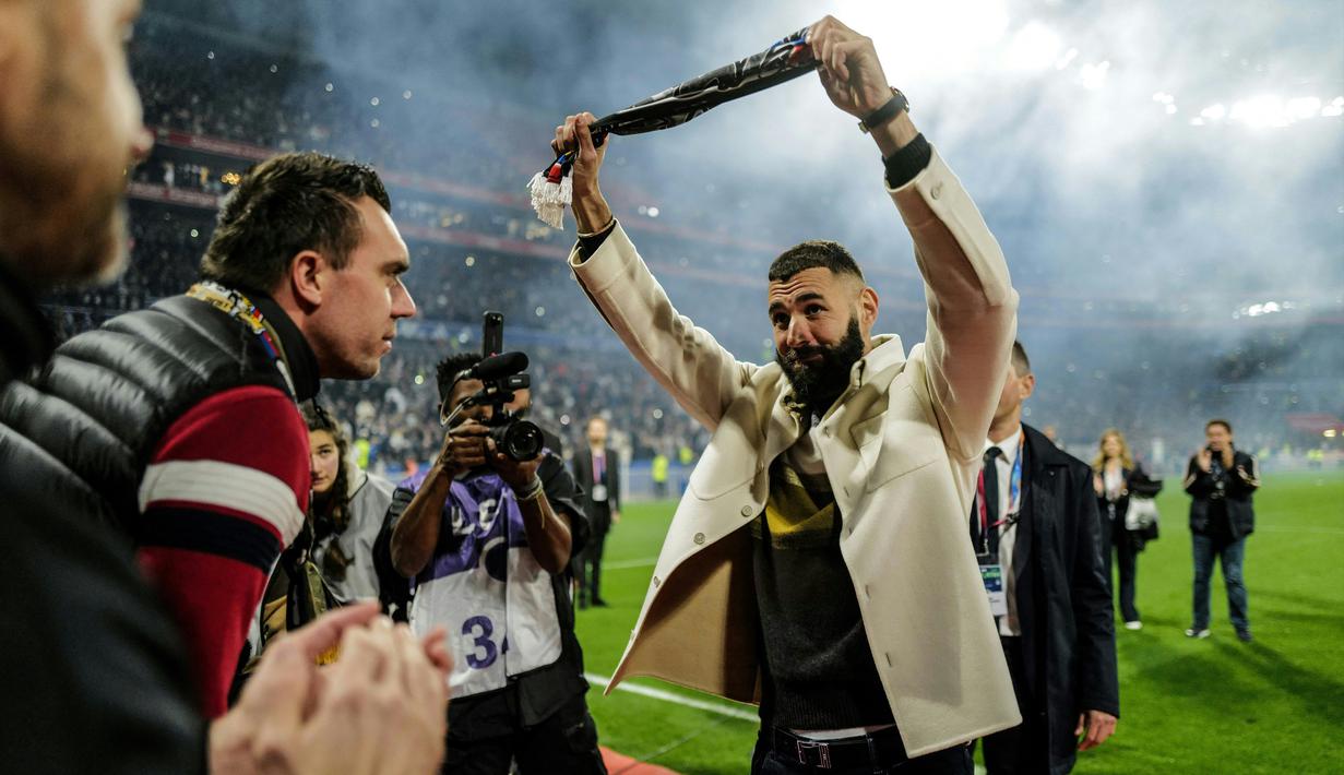 Pemain Real Madrid Karim Benzema (tengah) memberi isyarat kepada para penggemar saat penyerahan trofi Ballon d'Or miliknya pada babak pertama pertandingan sepak bola L1 Prancis antara Olympique Lyonnais (OL) dan OGC Nice di Stadion Groupama, Decines-Charpieu, Prancis, 11 November 2022. Momen itu juga menandai peringatan 35 tahun Bad Gones, fans utama pendukung Lyon. (OLIVIER CHASSIGNOLE/AFP)