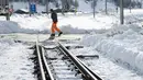 Seorang petugas memeriksa kondisi rel kereta api yang tertutup salju tebal di salah satu resor ski paling populer di Swiss (10/1). Sekitar 13.000 wisatawan terjebak akibat bencana tersebut. (AFP Photo/Fabrice Coffrini)