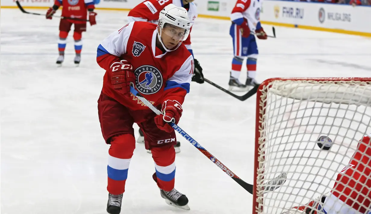 Presiden Rusia, Vladimir Putin saat berusaha memasukan bola saat bermain hoki dalam pertandingan persahabatan Night League di Sochi, Rusia, (10/5). Putin bermain bersama tim "Hockey Legends" dan berhasil menang 17-6. (AFP Photo/Pool/Yuri Kochetkov) 