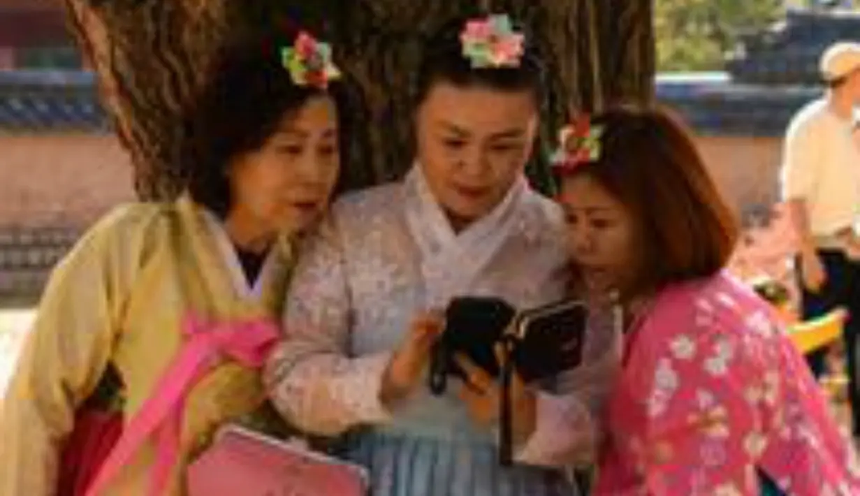 Sejumlah pengunjung mengenakan pakaian tradisional hanbok berada di bawah pohon ginkgo di istana Gyeongbokgung di Seoul (31/10). Pohon ini juga memiliki berbagai kegunaan dalam pengobatan tradisional dan sebagai sumber makanan. (AFP Photo/Ed Jones)