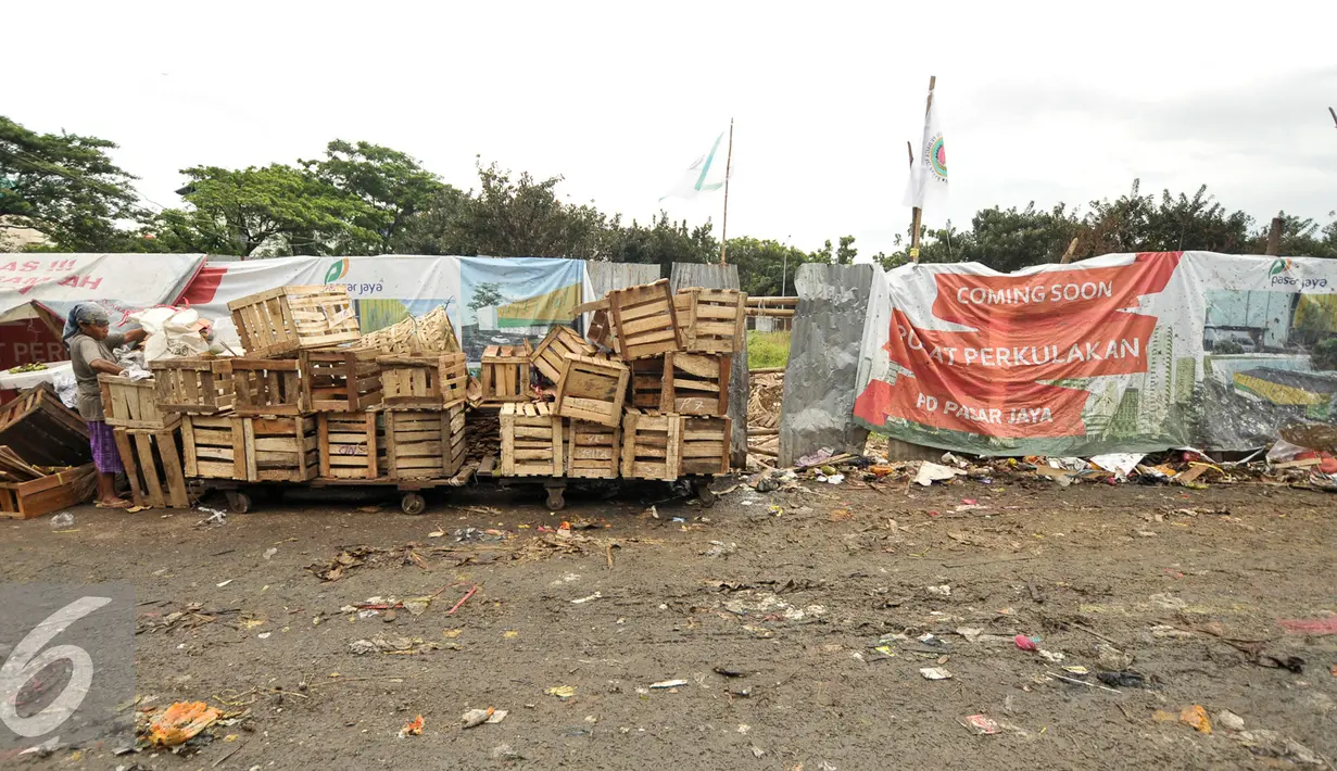 Warga merapihkan peti buah di samping lokasi pembangunan pusat perkulakan, Pasar Induk, Kramat Jati, Jakarta, Senin (16/1). Sebelumnya, pembangunan pusat perkulakan ini ditargetkan selesai pada Desember 2016 atau Januari 2017. (Liputan6.com/Yoppy Renato)
