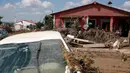 Orang-orang berdiri di balkon rumah yang terendam banjir yang dipicu badai dan hujan deras di desa Bourtzi di pulau Evia, Yunani, Senin (10/8/2020). Satu orang masih hilang, sementara banjir memblokir jalan serta merusak rumah-rumah di pulau di timur laut Athena itu. (AP Photo/Thanassis Stavrakis)