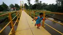 Seorang anak berlari di jembatan gantung di kawasan Tanjung Barat, Jakarta Selatan, Senin (22/5). Desain konstruksi jembatan tersebut dinilai tidak aman bagi keselamatan. (Liputan6.com/Immanuel Antonius)