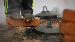 Pekerja migran India berdiri di atas batu bata dan menghangatkan dirinya di atas tungku di sebuah pabrik batu bata di pinggiran Kathmandu. Ribuan pekerja migran India datang ke Nepal untuk bekerja di pabrik batu bata. (AP Photo/Niranjan Shrestha)