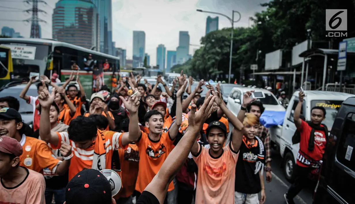 Suporter Persija bersorak saat menuju stadion Gelora Bung Karno, Jakarta, Minggu (9/12). Antusiasme ribuan suporter Persija bersiap mendukung tim kesayangannya bertanding melawan Mitra Kukar. (Liputan6.com/Faizal Fanani)