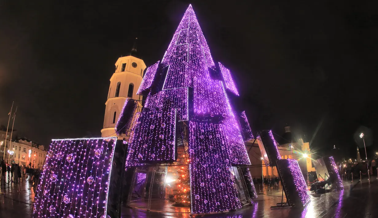 Pohon Natal yang menyala terlihat di dekat katedral di Vilnius, Lithuania pada 28 November 2020. Pohon natal raksasa yang dihiasi berbagai ornamen lampu hias tersebut membuat kawasan di ibu kota Lithuania menjadi terang. (PETRAS MALUKAS / AFP)