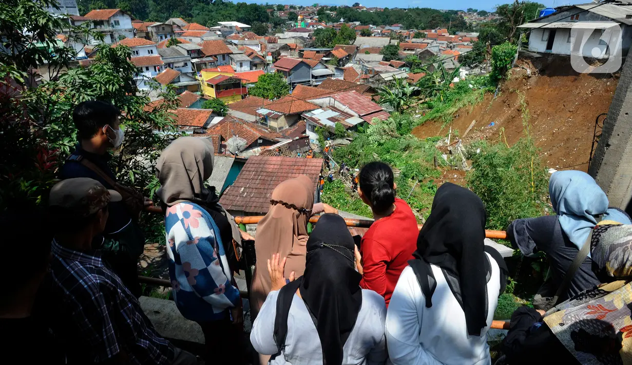 Warga melihat proses pencarian korban yang tertimbun tanah longsor di Kampung Kebon Jahe, Kelurahan Kebon Kelapa, Kecamatan Bogor Tengah, Kota Bogor, Kamis (13/10/2022). Lokasi yang berada di permukiman padat penduduk dengan struktur bangunan yang tidak tertata baik dan kemiringan yang curam, menyebabkan mudah longsor. berhasil dievakusi dalam kondisi selamat. (merdeka.com/Arie Basuki)