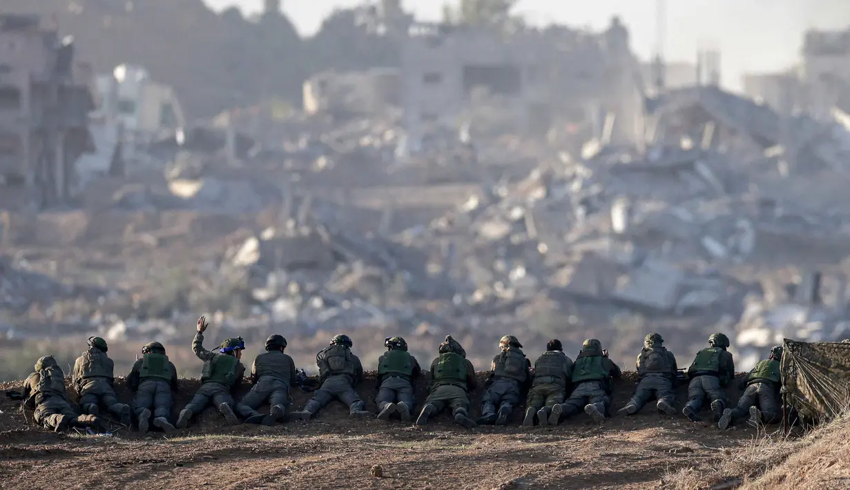 Sebuah foto yang diambil di Israel selatan dekat perbatasan dengan Jalur Gaza pada 11 Desember 2023, menunjukkan tentara Israel berjaga di sebuah bukit yang menghadap ke Gaza utara, di tengah pertempuran yang terus berlanjut antara Israel dan kelompok militan Hamas. (Menahem KAHANA/AFP)