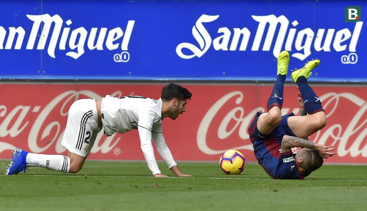 Gelandang Real Madrid, Marco Asensio, menjatuhkan bek Eibar. Paulo Oliveira, pada laga La Liga di Stadion Ipurua, Eibar, Sabtu (24/11). Eibar menang 3-0 atas Madrid. (AFP/Ander Gillenea)