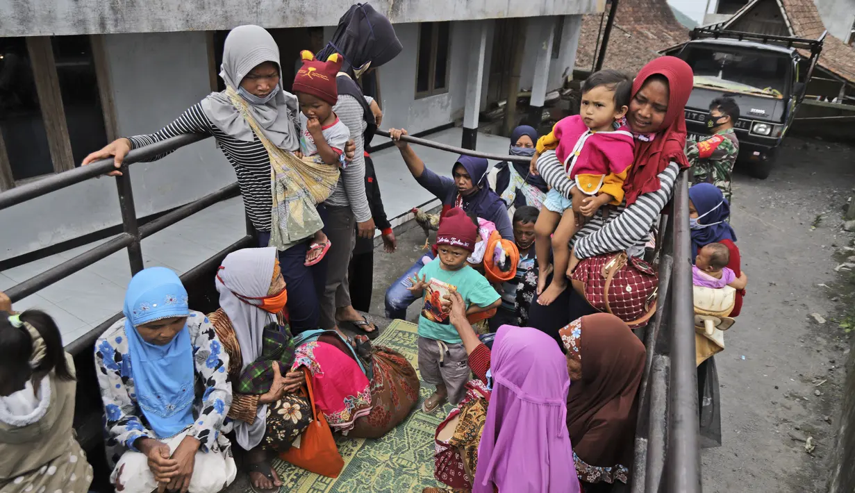 Perempuan dan anak-anak menaiki mobil bak terbuka untuk dievakuasi dari rumah mereka di lereng Gunung Merapi, di Krinjing, Jawa Tengah, Jumat (6/11/2020). Evakuasi dilakukan bagi warga lereng Merapi menyusul peningkatan status aktivitas vulkanik gunung tersebut. (AP Photo/Taufiq Rozzaq)