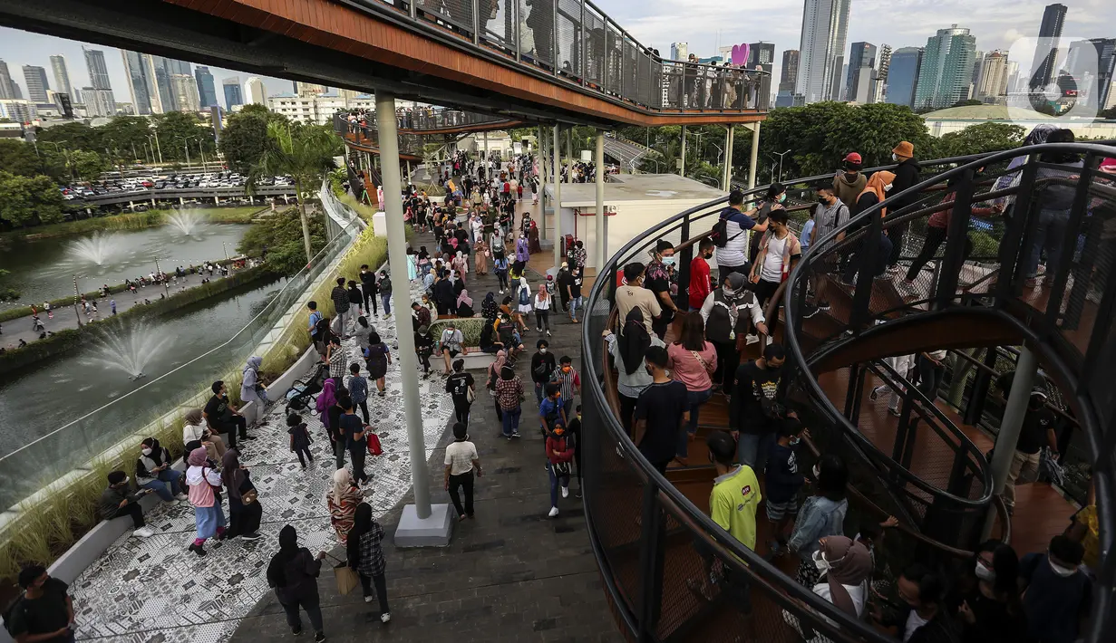 Warga mengisi libur Tahun Baru dengan menikmati pemandangan Kota Jakarta dari Skywalk Senayan Park, Sabtu (1/1/2022). Warga ramai-ramai datang untuk berburu foto pada spot-spot yang instagramable di Skywalk Senayan Park. (Liputan6.com/Johan Tallo)