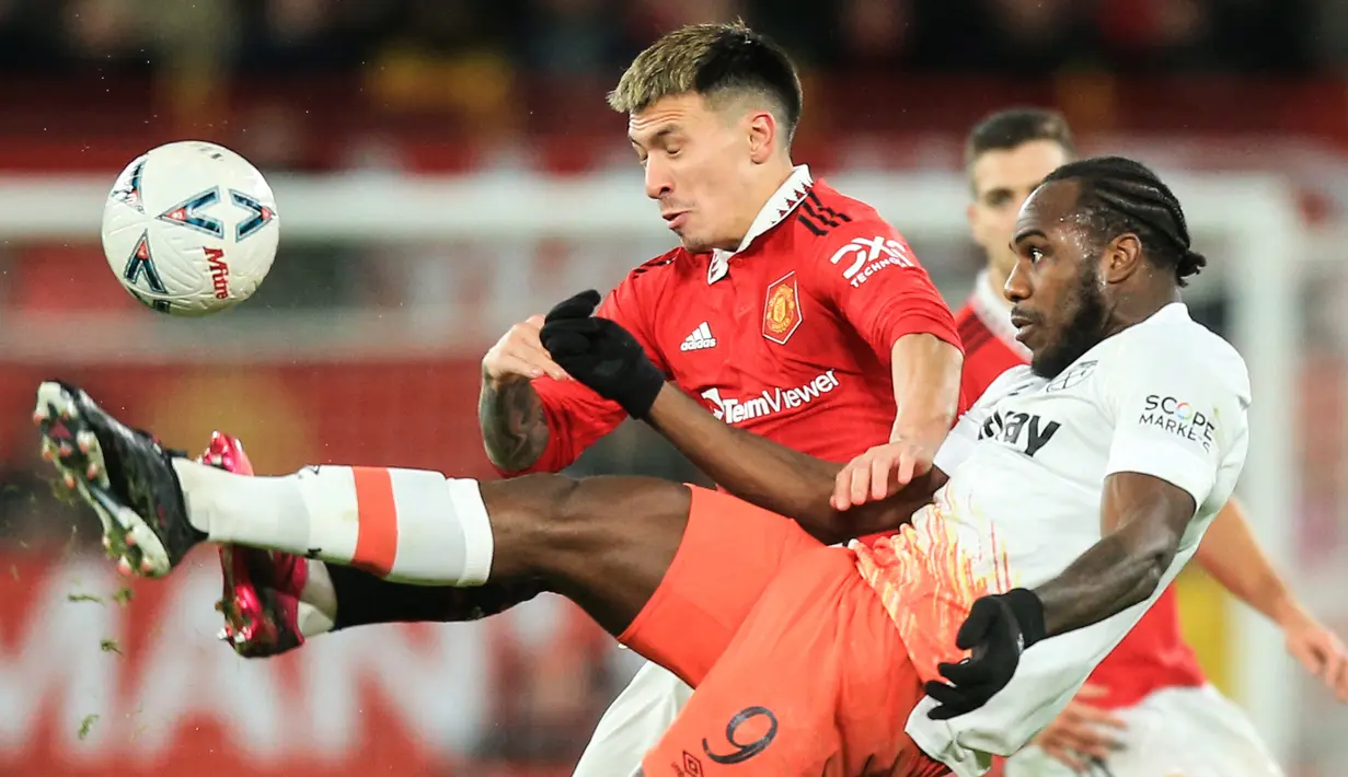 Bek Manchester United atau MU  Lisandro Martinez (kiri) berebut bola dengan gelandang West Ham United Michail Antonio pada putaran kelima Piala FA di Old Trafford, Kamis (2/3/2023) dinihari WIB. Duel Man United vs West Ham  tuntas dengan skor 3-1. (Lindsey Parnaby / AFP)