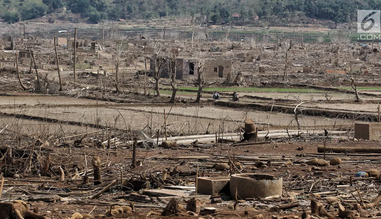 Warga melintasi bangunan di Waduk Jatigede, Desa Cipaku, Sumedang, Jawa Barat, Senin  (17/9). Musim kemarau panjang menyebabkan Waduk Jatigede surut sehingga puing bangunan Desa Cipaku yang tenggalam kembali terlihat. (Liputan6.com/Herman Zakharia)