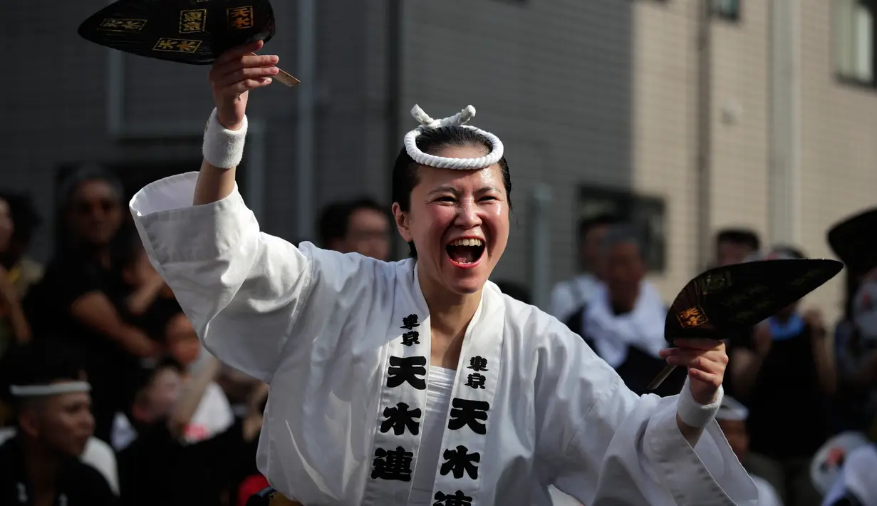 Seorang penari wanita menghibur penonton selama festival tari Koenji Awa-Odori di kawasan Koenji, Tokyo pada 24 Agustus 2019. Ribuan orang menyaksikan tontonan musim panas yang diadakan pada akhir pekan terakhir bulan Agustus setiap tahun selama dua hari. (AP/Jae C. Hong)