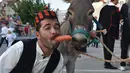 Seorang pria berbagi wortel dengan keledainya dalam kompetisi balap keledai tradisional ke-53 di Tribunj, Kroasia (29/8/2020). (Xinhua/Pixsell/Hrvoje Jelavic)