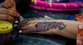 Seorang ahli kecantikan melukis 'Henna' tradisional di tangan pelanggan untuk perayaan Idul Fitri, yang menandai berakhirnya bulan suci Ramadan, di Rawalpindi, Pakistan, Rabu 18 Maret 2026. (AP Photo/Anjum Naveed)