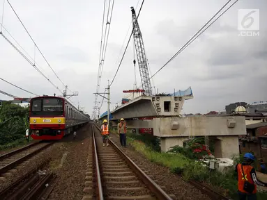 Kereta melintas disamping pembangunan kontruksi jalur DDT di Jakarta, Jumat (13/4). Menhub Budi Karya Sumadi menargetkan penyelesaian pembangunan proyek infrastruktur jalur DDT Manggarai- Cikarang selesai pada 2020. (Liputan6.com/Johan Tallo)