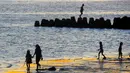 Hamparan pasir putih kecoklatan yang halus menyambut setiap wisatawan yang datang. Pasirnya nyaman untuk berjalan tanpa alas kaki, sementara deburan ombak memberikan nuansa rileks khas pantai Bali. Area pantai yang cukup luas juga memungkinkan pengunjung duduk santai di tepi pantai, baik di atas pasir maupun di area penahan abrasi yang tersedia. Tampak dalam foto, aktivitas wisatawan menikmati waktu senja di Pantai Kelan, Badung, Bali. (merdeka.com/Arie Basuki)