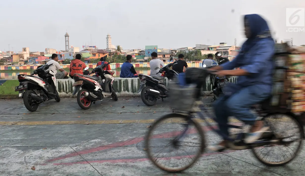 Warga memarkirkan sepeda motor di trotoar Danau Sunter, Jakarta, Senin (22/7/2019). Tidak adanya fasilitas parkir di kawasan tersebut menyebabkan pengunjung Danau Sunter memarkirkan sepeda motor mereka di sepanjang trotoar sehingga mengganggu akses pejalan kaki. (merdeka.com/Iqbal Nugroho)