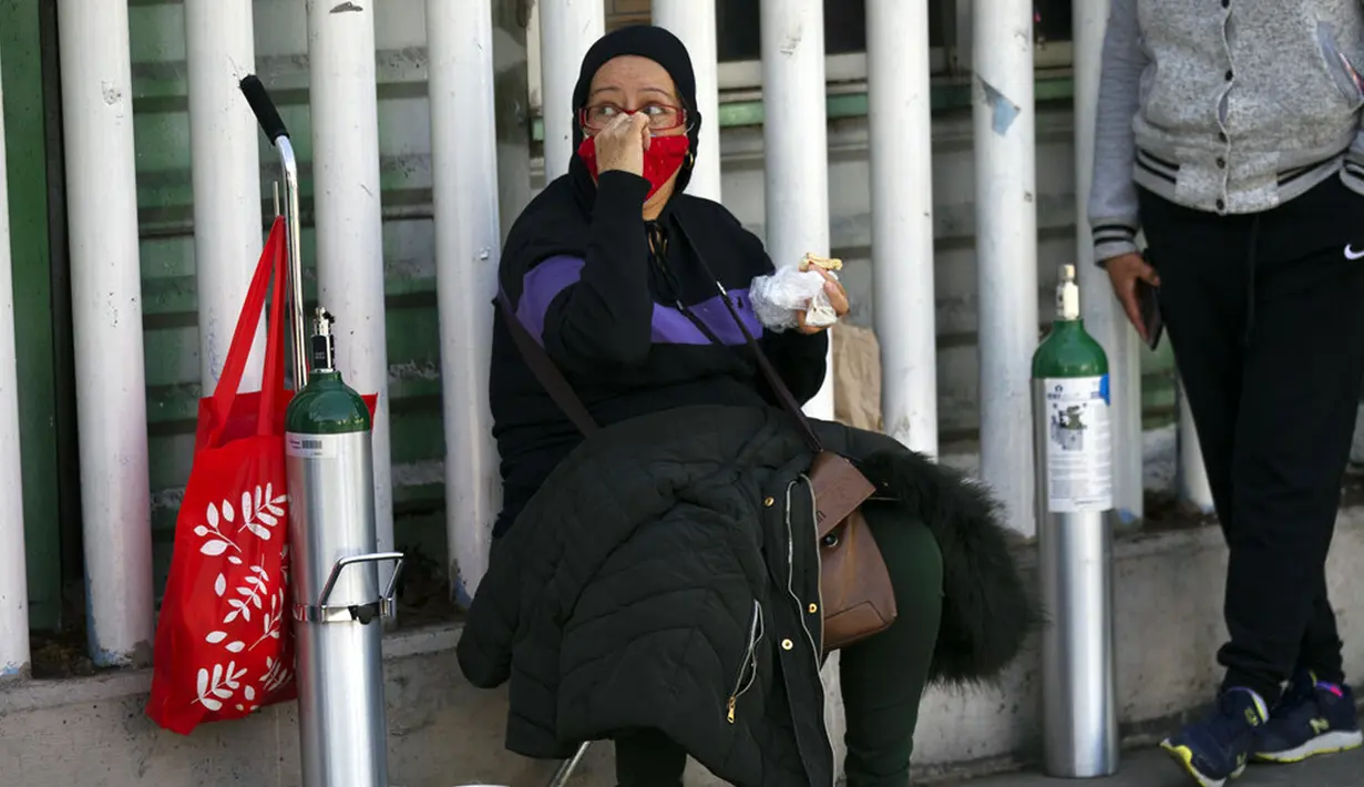 Seorang wanita menunggu untuk mengisi ulang tangki oksigen bagi kerabatnya yang menderita COVID-19 di Distrik Iztapalapa, Mexico City, Meksiko, Selasa (26/1/2021). Mexico City menawarkan isi ulang oksigen gratis untuk pasien COVID-19. (AP Photo/Marco Ugarte)