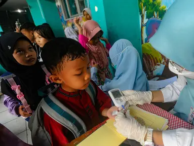 Tenaga medis dari Puskesmas Ciputat melakukan tes gula saat kegiatan pengecekan kesehatan murid di Sekolah Dasar Negeri (SDN) 04 Ciputat, Tangerang Selatan, Banten, Jumat (9/8/2024). (merdeka.com/Arie Basuki)