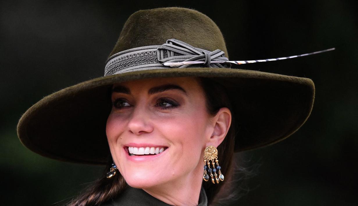Kate Middleton, Princess of Wales dari Inggris tersenyum usai kebaktian Natal di Sandringham, Norfolk, Inggris pada 25 Desember 2022. Ibu tiga anak ini tampak bergaya dalam balutan coat hijau olive panjang yang bagian bawahnya lebar dari koleksi Alexander McQueen. (AFP/Daniel Leal)