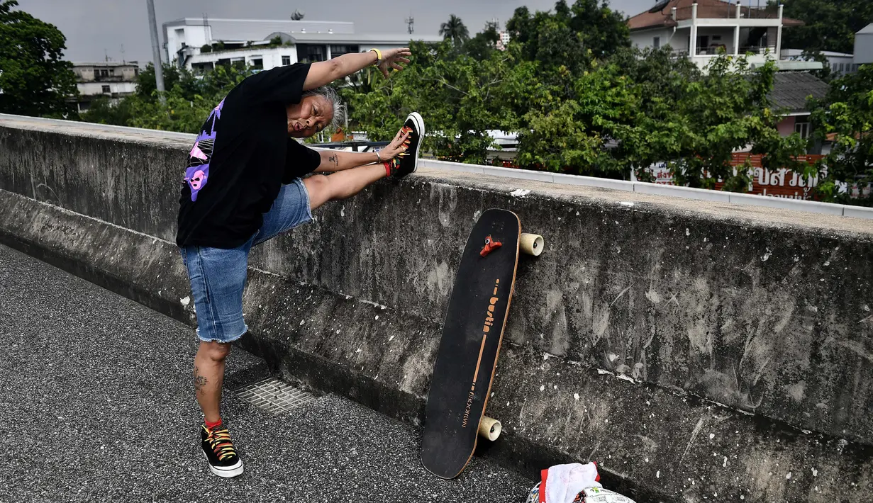 Longboarder dan penderita kanker Nongluck Chairuettichai, juga dikenal sebagai Jeab, melakukan pemanasan sebelum latihan di Bangkok pada 9 September 2020. Kegiatan ini dilakukan Jeab yang berusia 63 tahun sebagai jalan pemulihan dari kanker payudara yang dideritanya. (Lillian SUWANRUMPHA/AFP)