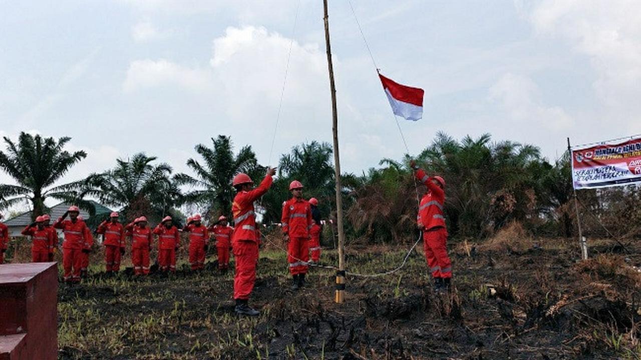 Personel Manggala Agni mengibarkan bendera dalam upacara kemerdekaan di lokasi kebakaran lahan.