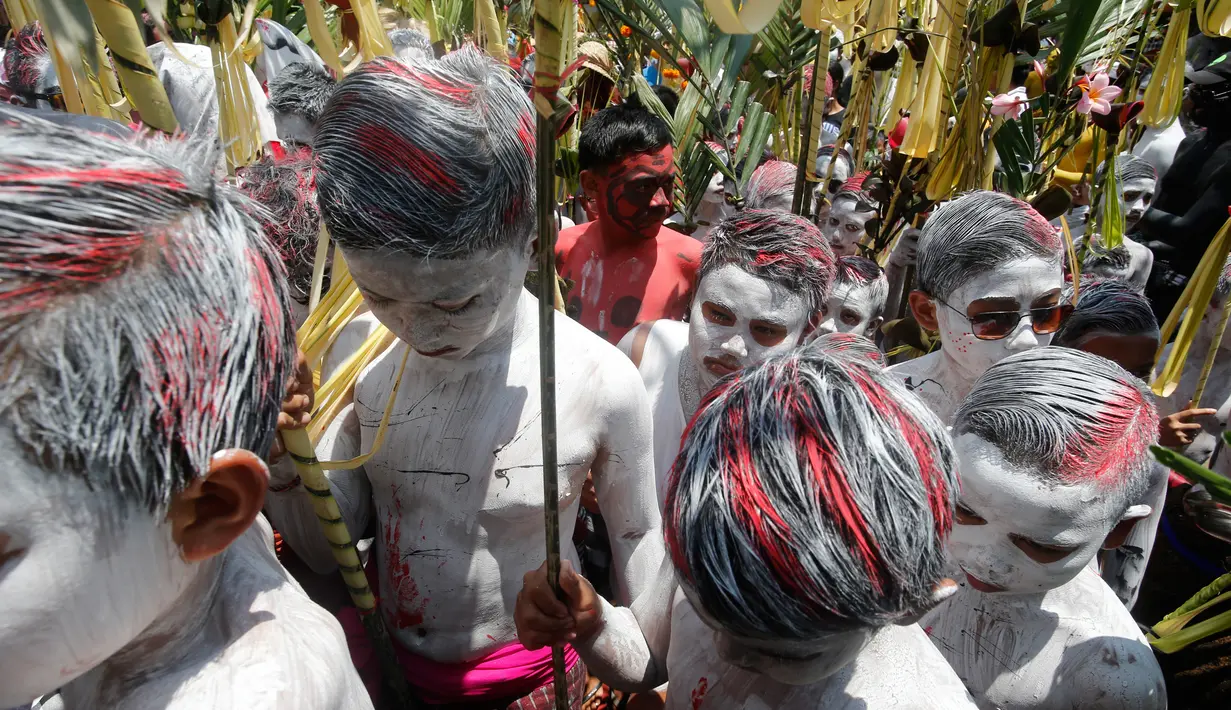 Para pemuda berjalan menuju pura saat ritual Hindu yang disebut "Grebeg" di Desa Tegallalang, Bali, Rabu (30/1). Dalam ritual dua tahunan ini, para pemuda berkeliling kampung dengan riasan tubuh warna-warni untuk menangkal Roh jahat. (AP/Firdia Lisnawati)