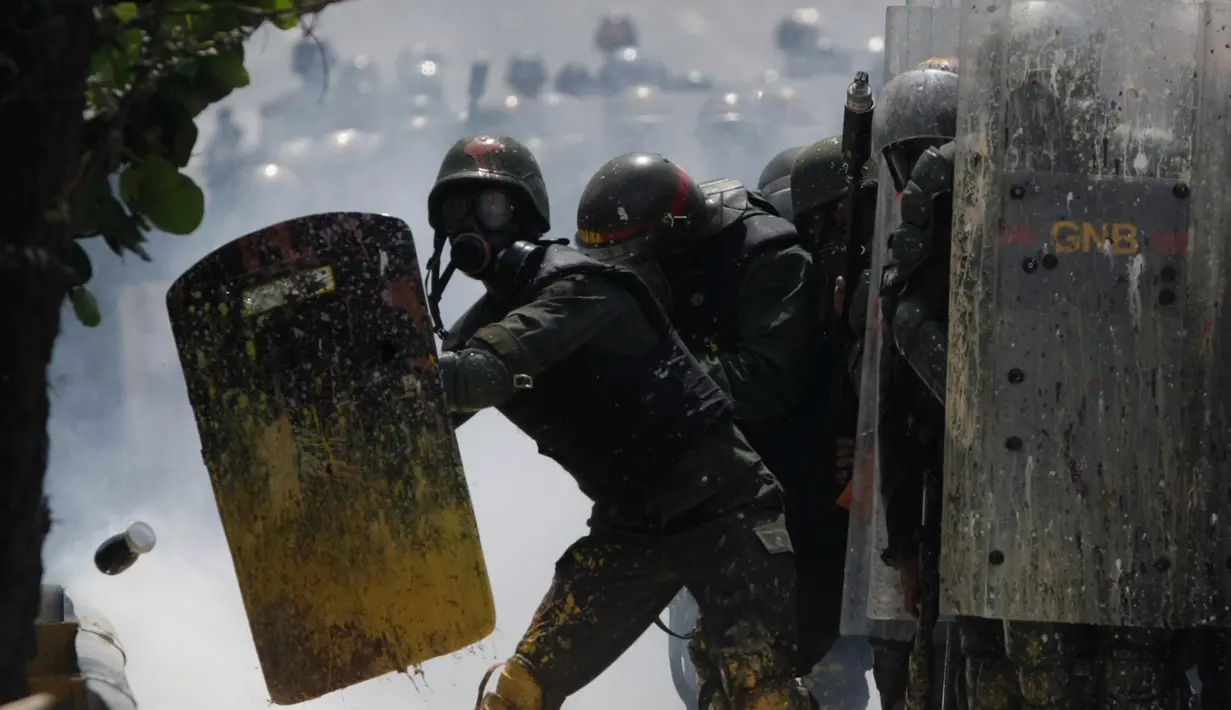 Petugas Garda Nasional Venezuela melindungi diri dari sebotol kotoran manusia atau tinja di Caracas, 10 Mei 2017. Demonstran anti-pemerintah kini menggunakan bom 'poopootov' untuk menyerang petugas yang menghalangi jalannya demo. (AP Photo/Fernando Llano)