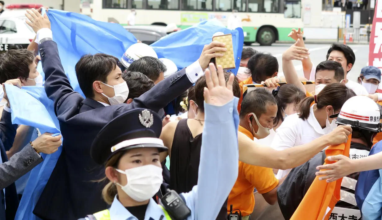Orang-orang bereaksi setelah tembakan di Nara, Jepang barat (8/7/2022). NHK dan Kyodo sama-sama melaporkan Abe dibawa ke rumah sakit dan tampaknya mengalami cardo-respiratory arrest-istilah yang digunakan di Jepang untuk menunjukkan tidak ada tanda-tanda vital, dan umumnya mendahului sertifikasi formal kematian oleh koroner. (Kyodo News via AP)