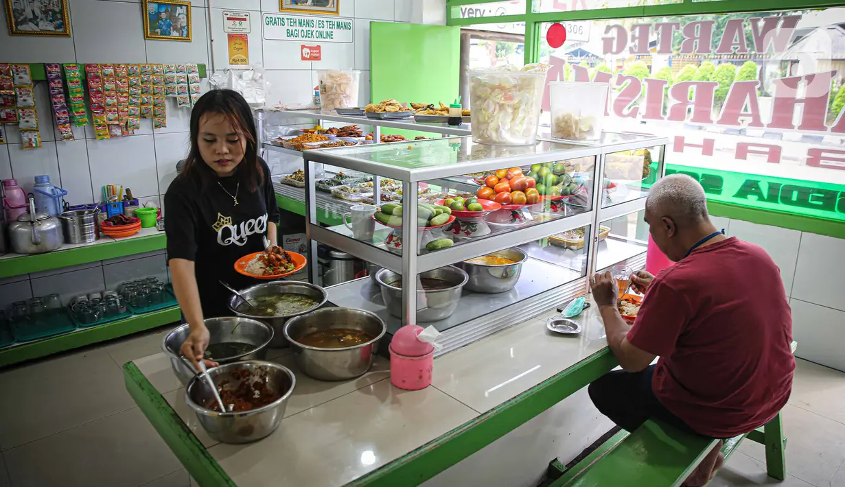 <p>Pekerja melayani pengunjung di rumah makan Warteg Bahari, Jakarta, Rabu (1/12/2021). Naiknya PPKM DKI menjadi level 2 mengubah banyak aturan di wilayah tersebut, salah satunya jam operasional warteg yang diizinkan hingga pukul 21.00 dengan kapasitas pengunjung 50 persen. (Liputan6.com/Faizal Fanani)</p>