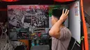 Seorang santri berjalan melewati layar TV yang menayangkan upaya pencarian korban hilang dari reruntuhan bangunan di sebuah pondok pesantren di Sidoarjo, Jawa Timur, Sabtu 4 Oktober 2025. (AP Photo/Achmad Ibrahim)