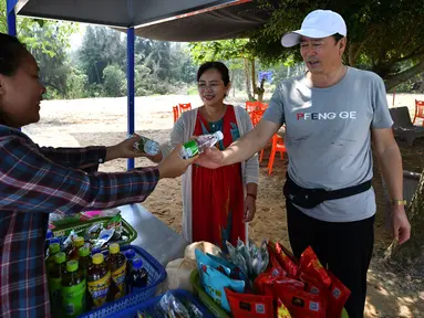 Sejumlah turis menukarkan sampah dengan dua botol air kemasan di Teluk Mulan, Kota Wenchang, Provinsi Hainan, China, 28 April 2020. (Xinhua/Guo Cheng)