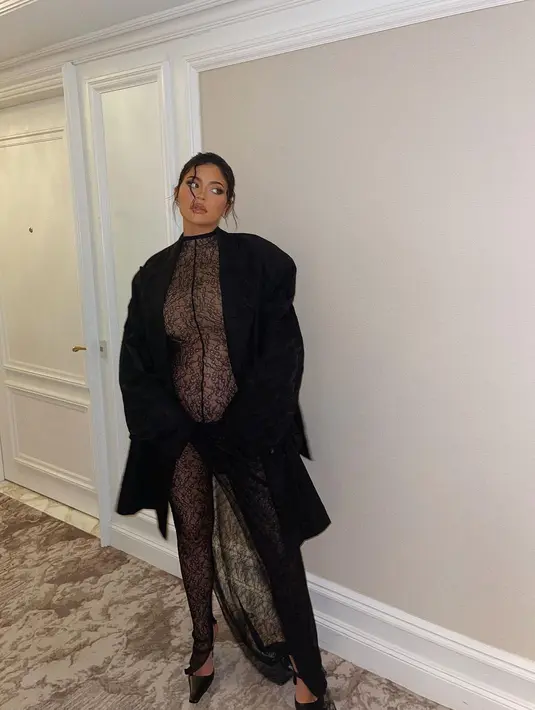 Kali ini, dalam dress semi transparan, Kylie Jenner tampil berani memperlihatkan baby bumpnya. Ia tumpuk dress semi transparan ini dengan coat bulu berwarna hitam dan memadukannya dengan heels hitam. Foto: Instagram.