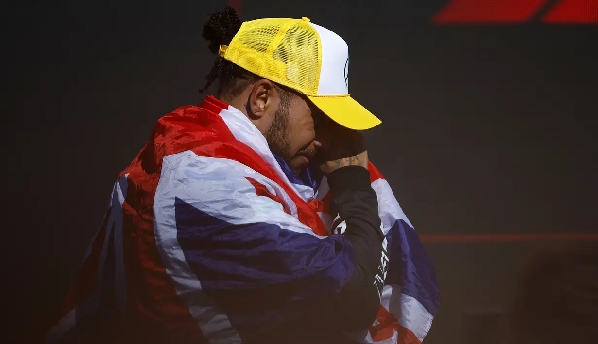 Pembalap Mercedes, Lewis Hamilton mengusap air matanya saat naik ke atas podium Formula 1 GP Inggris 2024 di Sirkuit Silverstone, Inggris, Minggu (08/07/2024). (AFP/Benjamin Cremel)