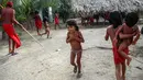 Anak-anak suku Waiapi berjalan di bawah hujan di desa Manilha di negara bagian Amapa, Brasil (14/10). Jumlah anggota suku Waiapi mencapai 1.615 orang, 905 orang diantaranya berada di delapan desa pedalaman Brasil. (AFP Photo/Apu Gomes)