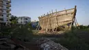 Sebuah kapal tradisional yang sedang dibangun berada di seberang jalan dari gedung-gedung bertingkat di Mandvi, Gujarat, India, Selasa (9/1/2024). (AP Photo/Ashwini Bhatia)