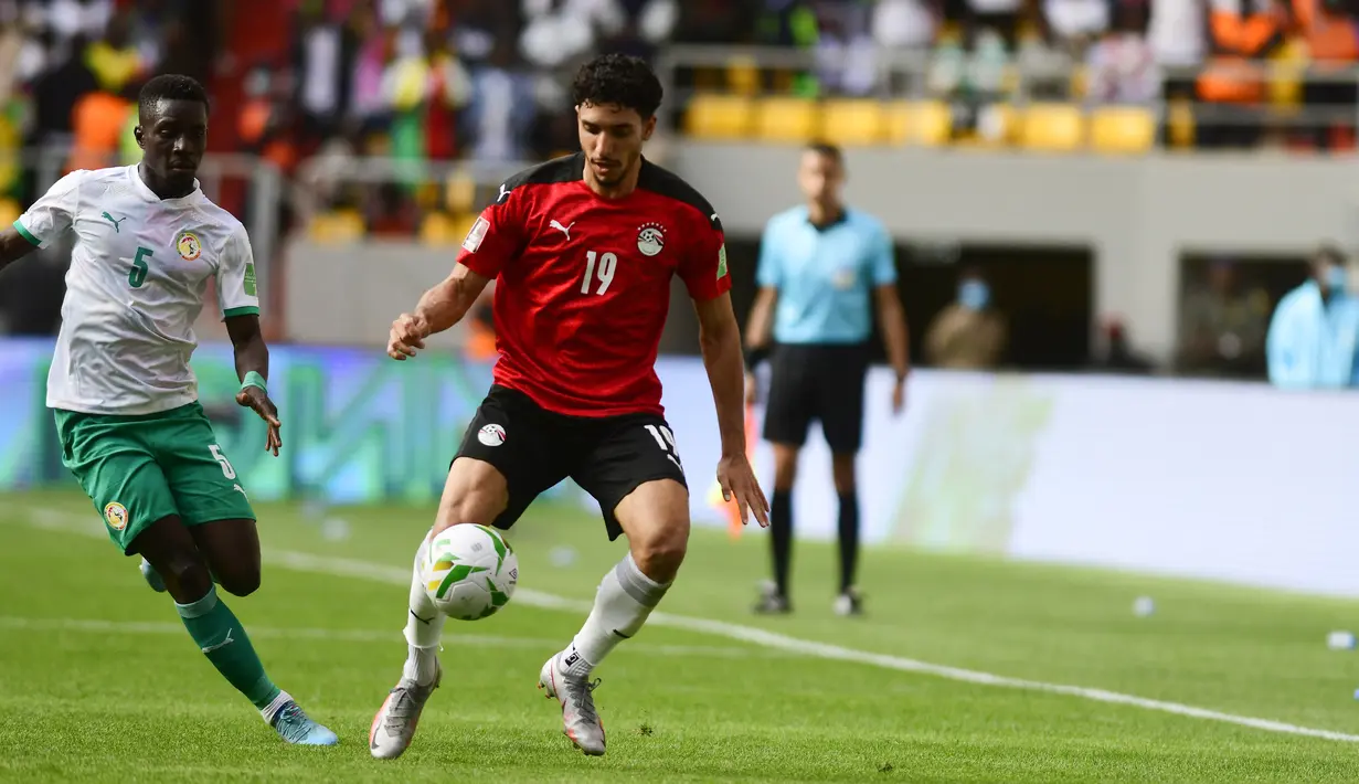 Penyerang Mesir Omar Marmoush berebut bola dengan gelandang Senegal Idrissa Gana Gueye pada Kualifikasi Piala Dunia 2022 zona Afrika di Stade Me Abdoulaye Wade, Rabu (30/3/2022) dini hari WIB. Senegal dipastikan lolos ke Piala Dunia 2022 setelah menang adu penalti atas Mesir 3-1. (SEYLLOU / AFP)