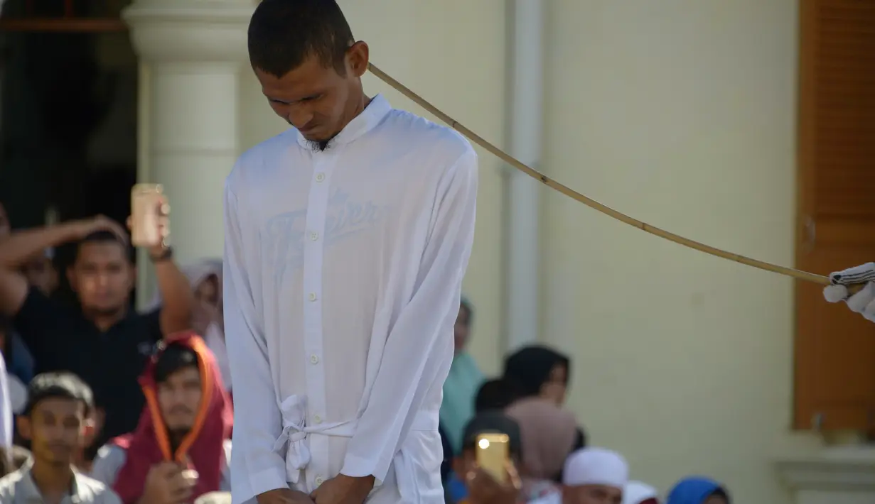 Petugas syariah mencambuk salah satu pasangan gay di depan Masjid Baiturrahim, Aceh (13/7). Nyakrab dan Rustam divonis hukuman cambuk sebanyak 90 kali, saat eksekusi cambukan dipotong menjadi 87 kali karena pengurangan masa tahanan. (AP Photo/Heri Juanda)