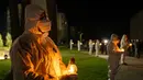 Orang-orang yang mengenakan pakaian pelindung putih memegang lilin selama upacara peringatan yang didedikasikan untuk petugas pemadam kebakaran dan pekerja yang meninggal setelah bencana nuklir Chernobyl, menjelang peringatan 40 tahunnya di Slavutych, Ukraina, Sabtu, 25 April 2026. (AP Photo/Dan Bashakov)