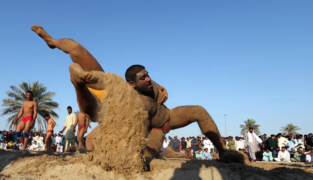 Seorang pegulat Pakistan membanting lawannya saat bertarung dalam kompetisi gulat Greco-Roman mingguan di Dubai (16/3). Mereka melakukan pertandingan gulat gaya kuno. (AFP Photo/Karim Sahib)