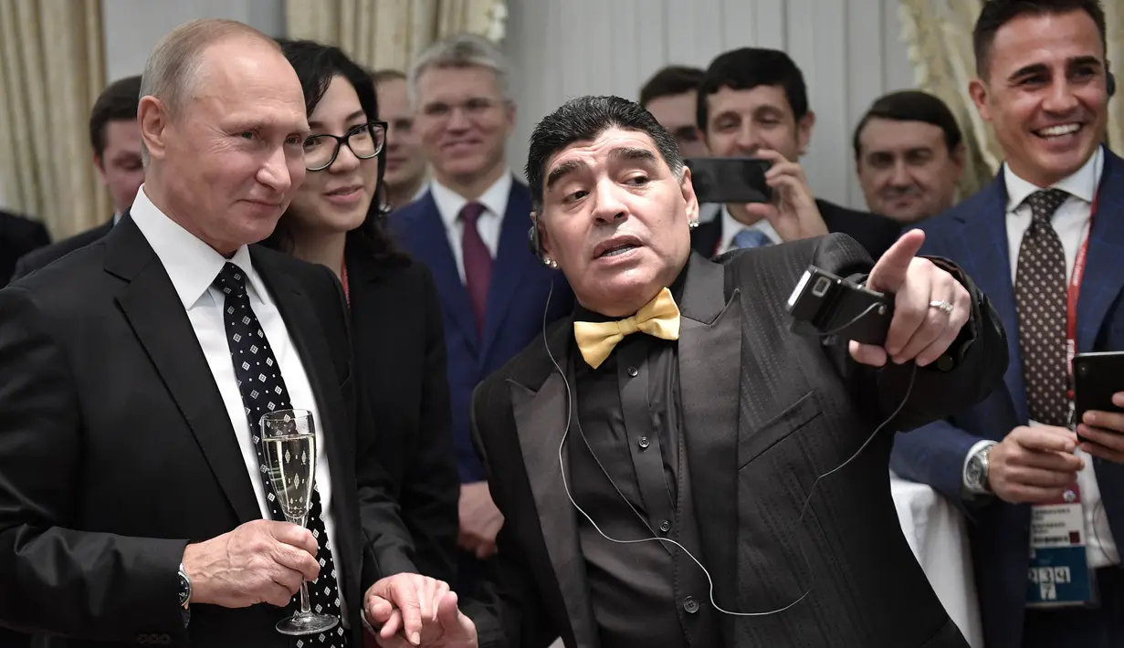 Legenda sepak bola, Diego Maradona berbincang dengan Presiden Rusia, Vladimir Putin, saat menghadiri Drawing Piala Dunia 2018 di Kremlin Palace, Jumat (1/12/2017). Acara tersebut dihadiri legenda sepak bola dunia. (AFP/Alexey Nikolsky)