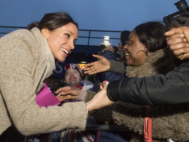 Meghan Markle tersenyum saat menyalami warga menyusul kunjungan Pangeran Harry ke stasiun radio Reprezent 107,3 FM di Brixton, London, Selasa, (9/1). Meghan dan Pangeran Harry dijadwalkan menikah musim panas ini. (AP Photo/Dominic Lipinski, Pool)