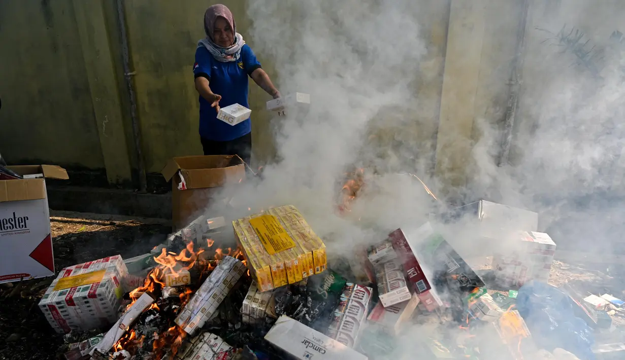 Petugas Bea dan Cukai membakar barang hasil penindakan berupa rokok impor ilegal saat pemusnahan di Banda Aceh, Aceh, Selasa (22/7/2025). (CHAIDEER MAHYUDDIN/AFP)