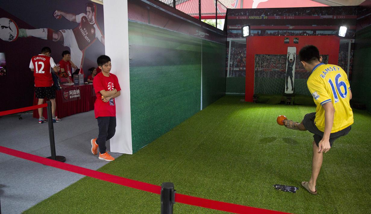 Seorang fans Arsenal menendang bola melewati penjaga gawang mekanik di Beijing, Jumat, (21/7/2017). Arsenal dan Chelsea akan bertanding dalam laga persahabatan. (AP/Ng Han Guan)
