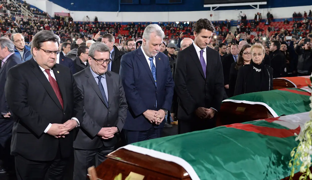 PM Kanada, Justin Trudeau (kanan) bersama Wali Kota Quebec, Philippe Couillard memberikan penghormatan terakhir kepada tiga dari enam korban penembakan di Masjid Quebec, di Montreal Olympic, Kamis (2/2). (Paul Chiasson/The Canadian Press via AP)