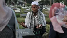 Seorang pria bernama Muhammad Hoir memimpin doa 'Talkin' untuk peziarah di Tempat Pemakaman Umum (TPU) Kemiri, Rawamangun, Jakarta, Selasa (15/5). (Merdeka.com/Iqbal S Nugroho)